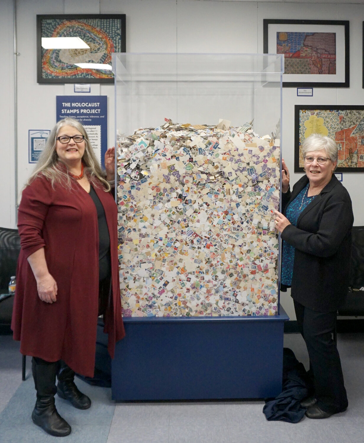 Jamie Droste, left, now retired, the former student life adviser at the Foxboro Regional Charter School, poses with retired teacher and Holocaust Stamps Project founder Charlotte Sheer with The Cube.